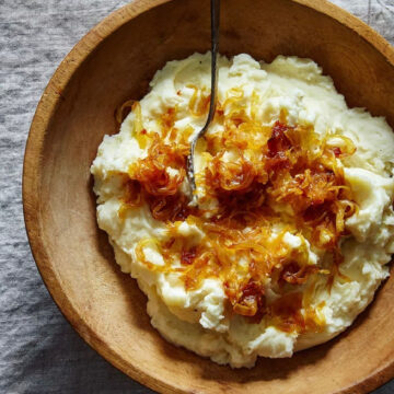 Mashed potatoes with caramelized onions and goat cheese in a wooden bowl.