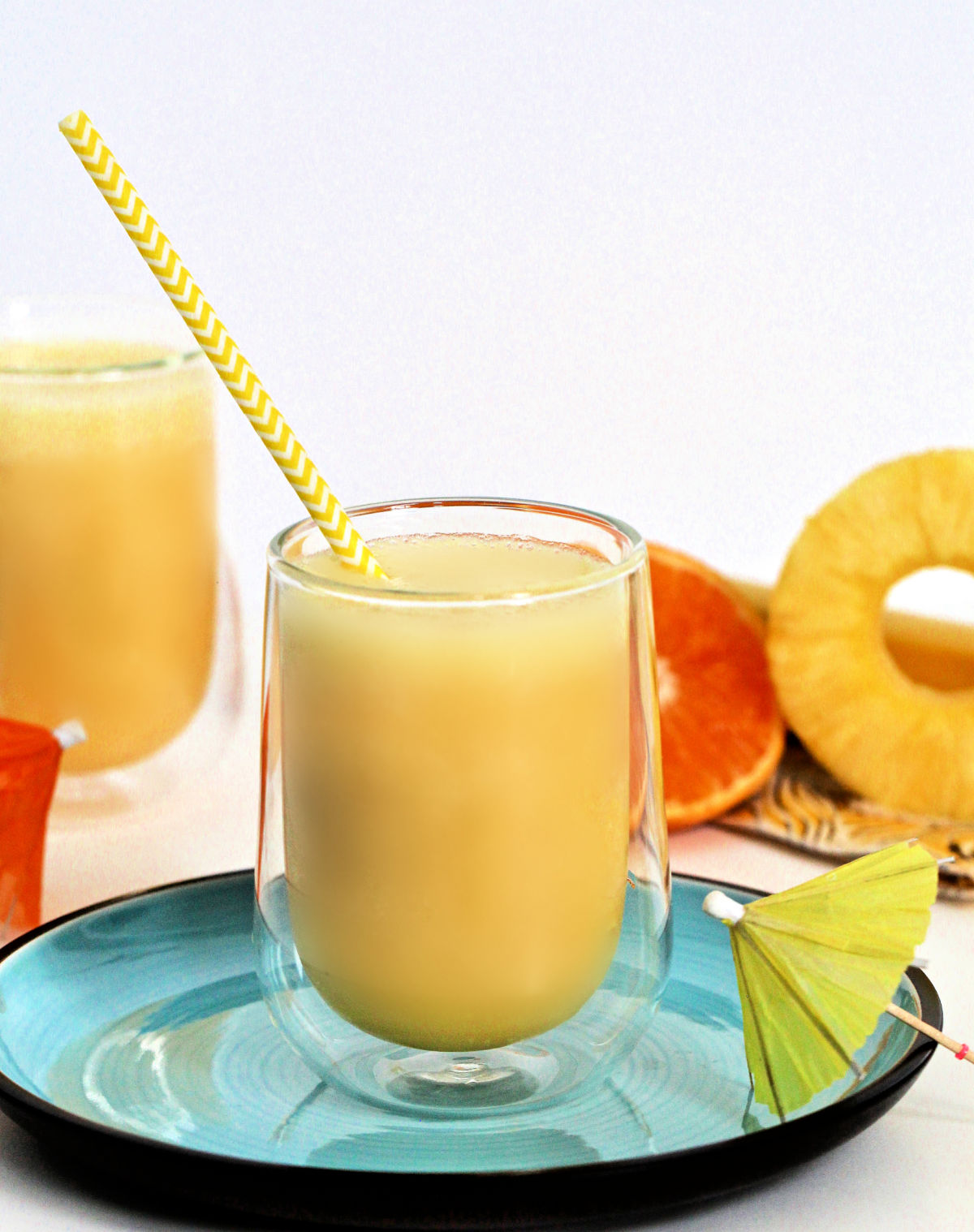 Smoothie in a glass with a yellow and white striped straw.