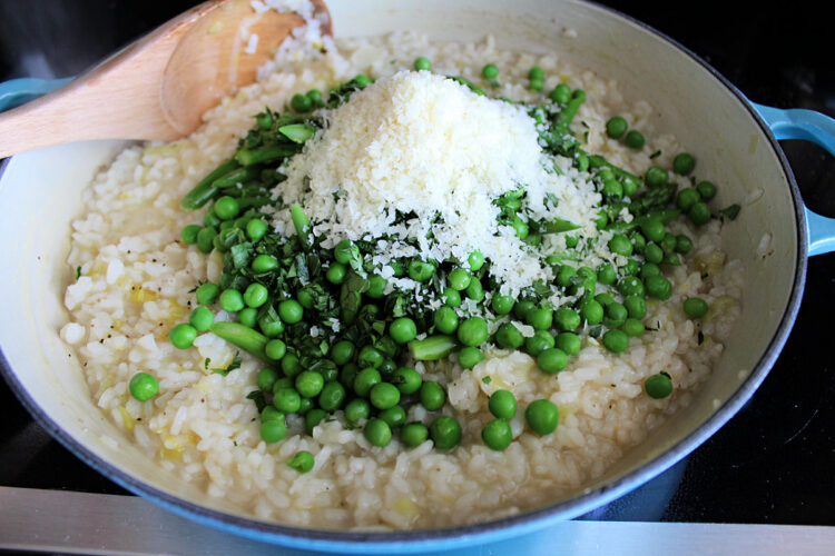 lemon risotto in skillet adding vegetables and cheese