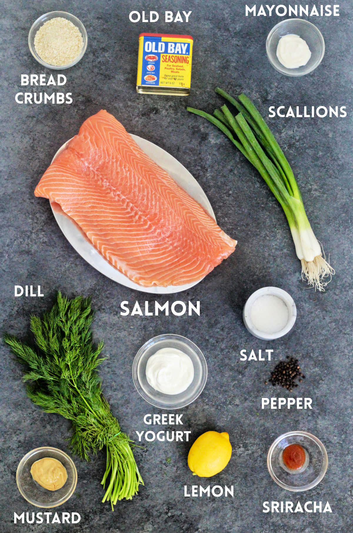 Ingredients for salmon burgers on a gray board.