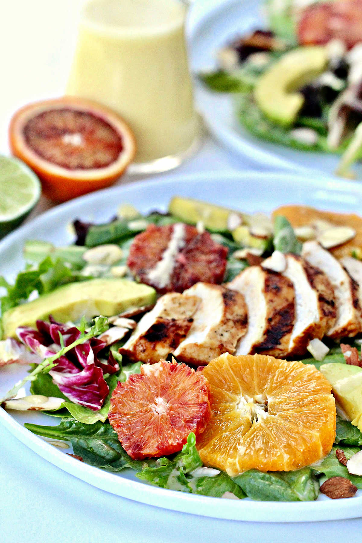Summer citrus salad with grilled chicken on a white plate.
