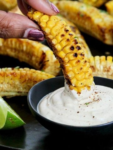 A corn rib being dunked into Southwest dipping sauce