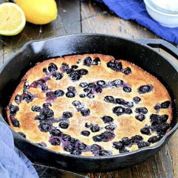 Blueberry Lemon Dutch Baby in cast iron skillet with blue napkin in background.