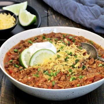 A bowl of turkey chili with shredded cheese and sour cream.