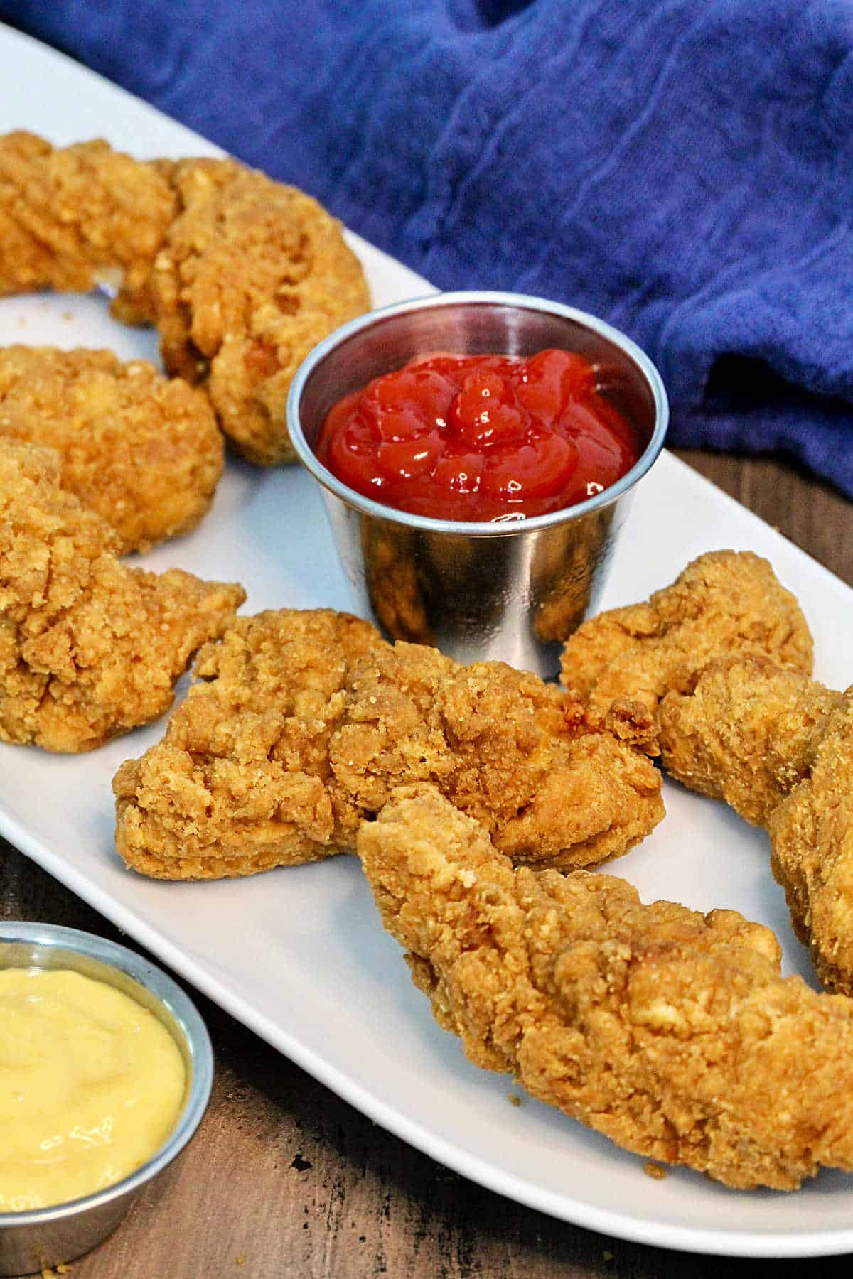 Chicken tenders on a plate with ketchup and honey mustard.