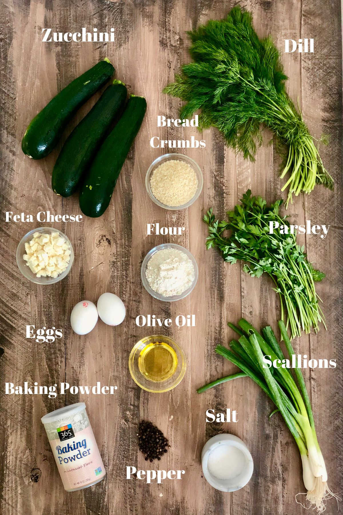 Ingredients for Greek zucchini fritters on a wooden board.