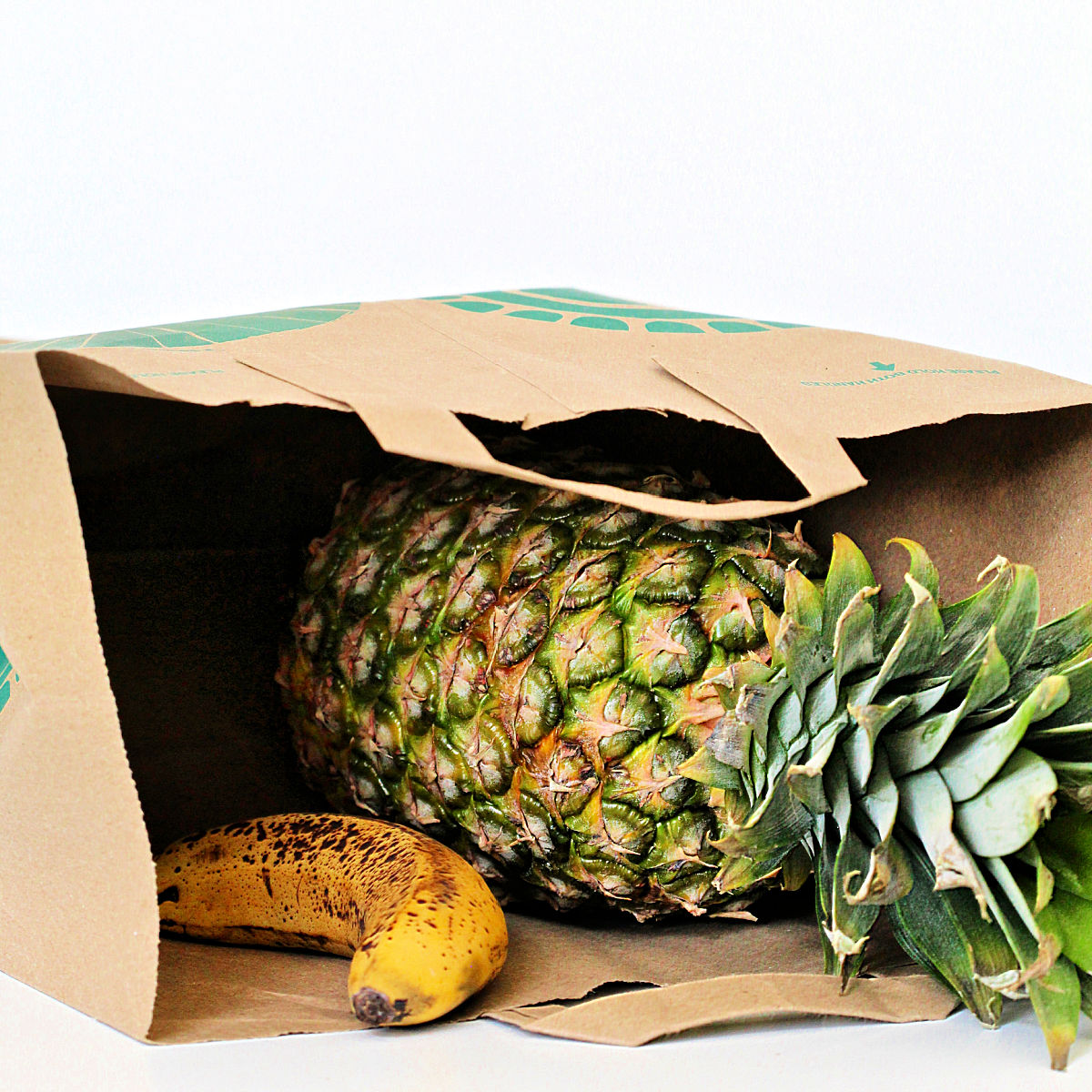 Pineapple in a paper bag with a banana.