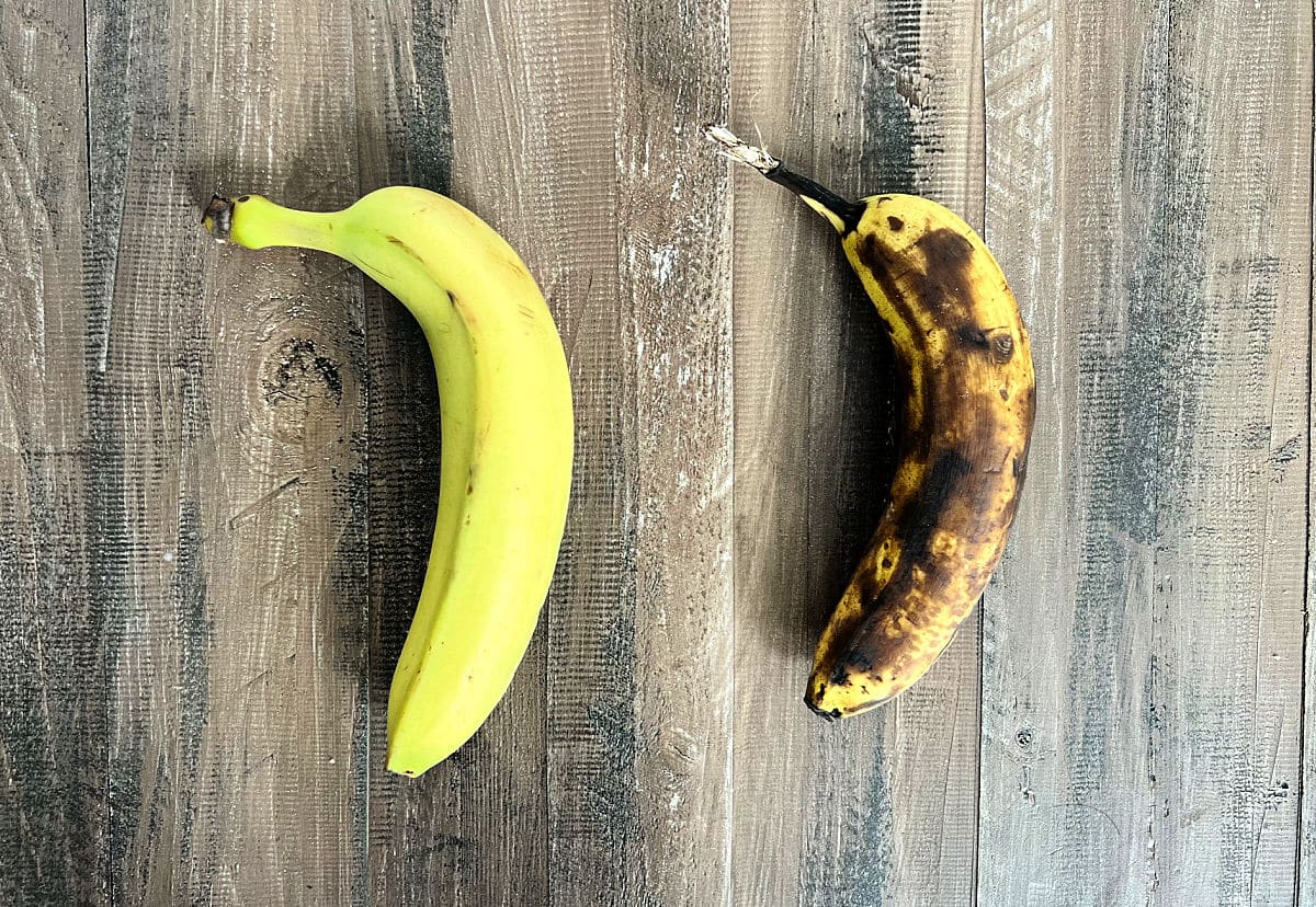 picture of a yellow banana and a brown banana on a wooden board.