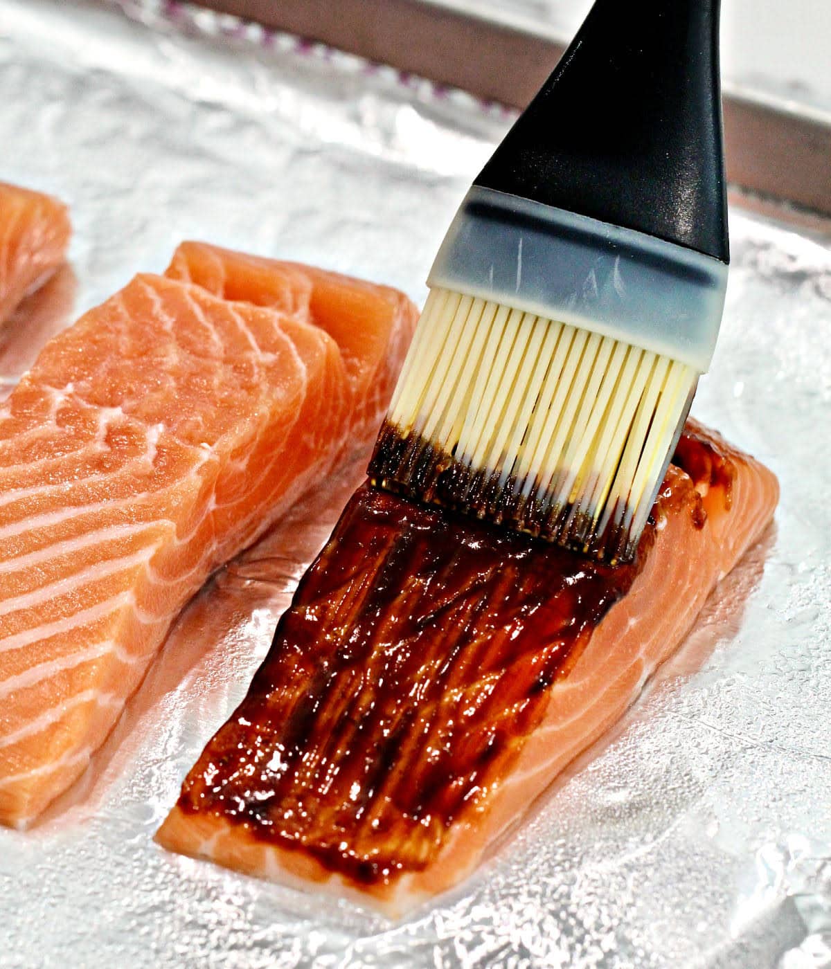 Brushing miso glaze on a piece of salmon.