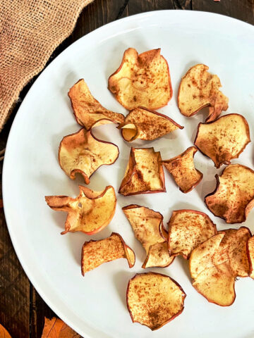 Air fryer apple chips on a white plate.