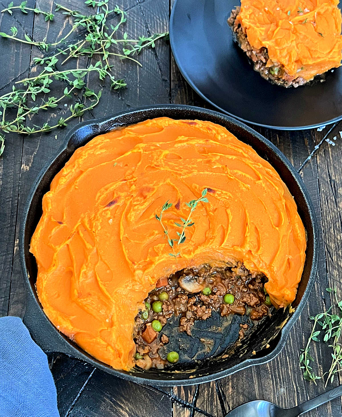 Overhead of sweet potato shepherd's pie in cast iron skillet with a piece scooped out.