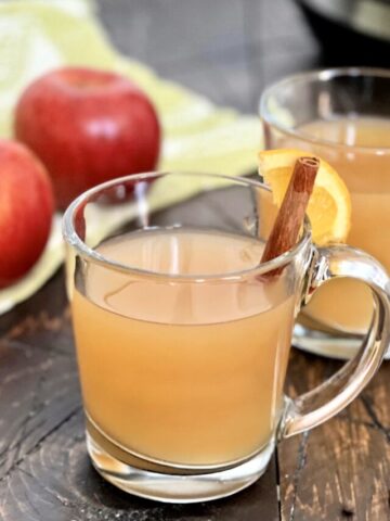 A glass of crock pot mulled cider with a cinnamon stick.