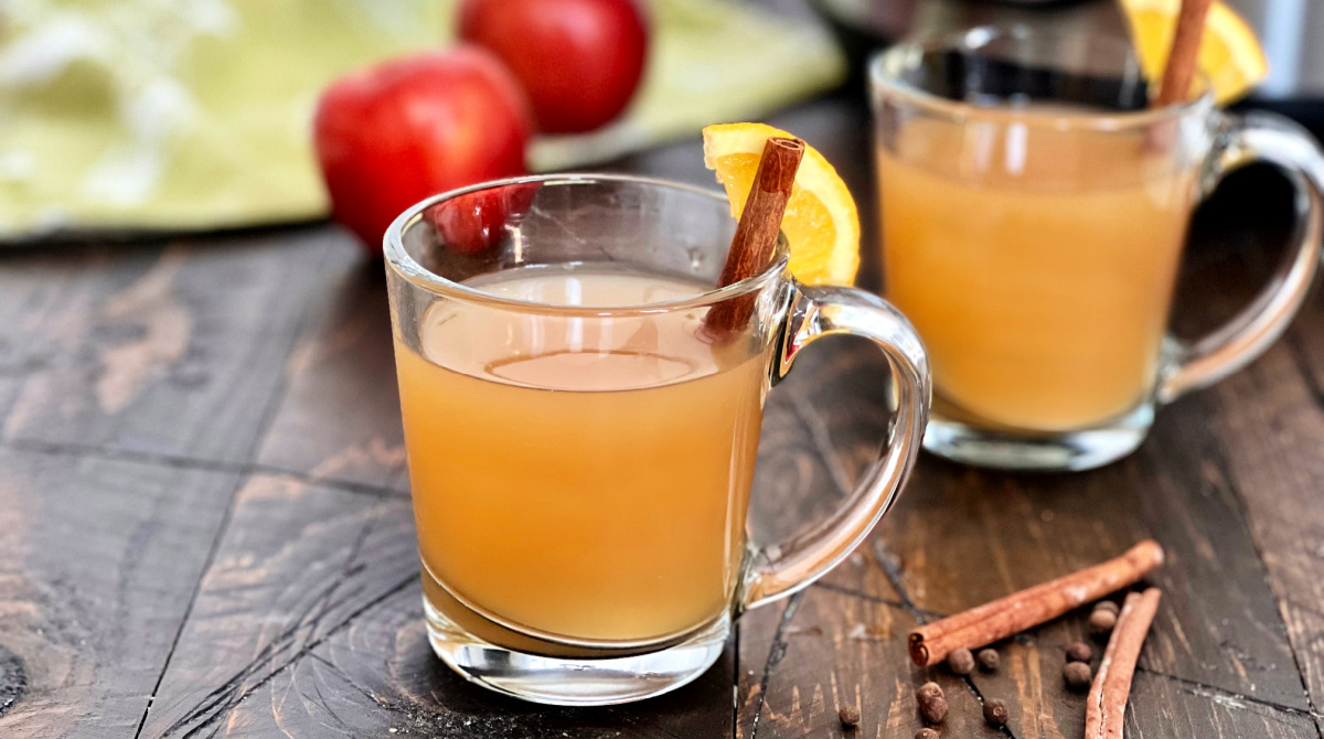 Two glasses of crock pot mulled cider with a cinnamon stick.