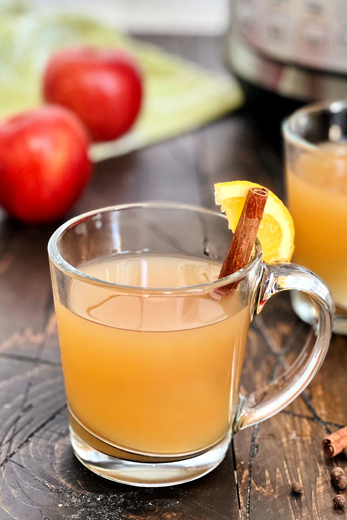 A glass of crock pot mulled cider with a cinnamon stick.
