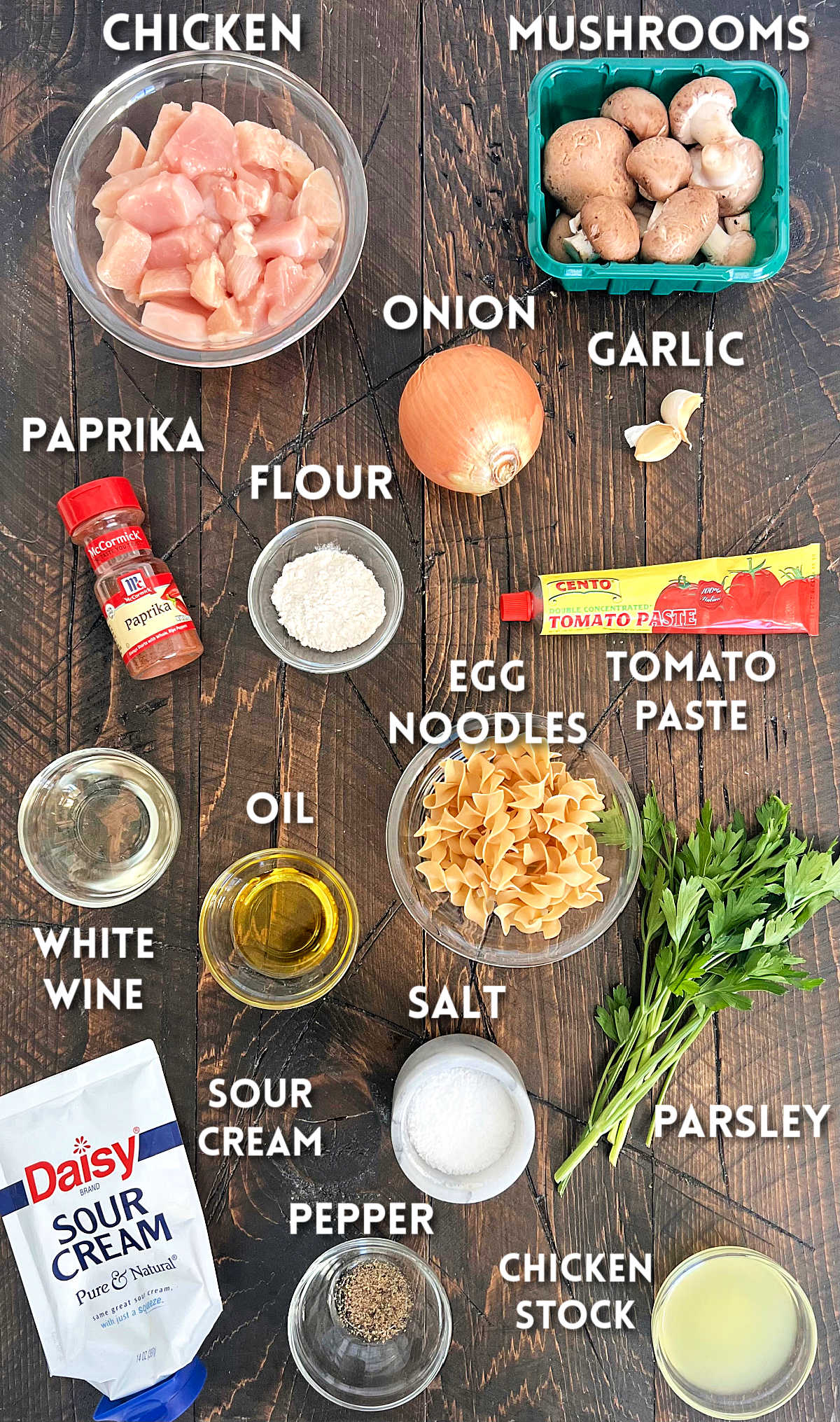 Ingredients for creamy paprika chicken on a brown board.