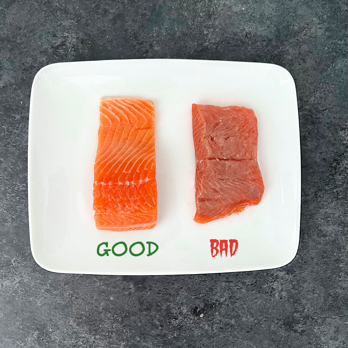 A piece of good salmon and a piece of bad salmon on a white plate.