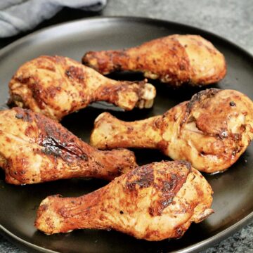 Air fryer chicken legs on black plate.