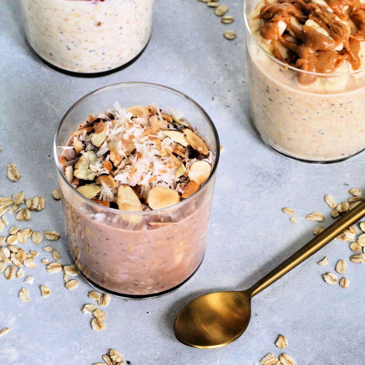 Varieties of protein overnight oats with a gold spoon.