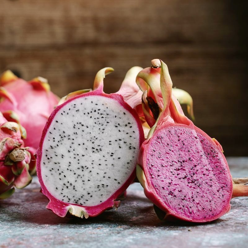 Pink and white dragon fruit on a board.