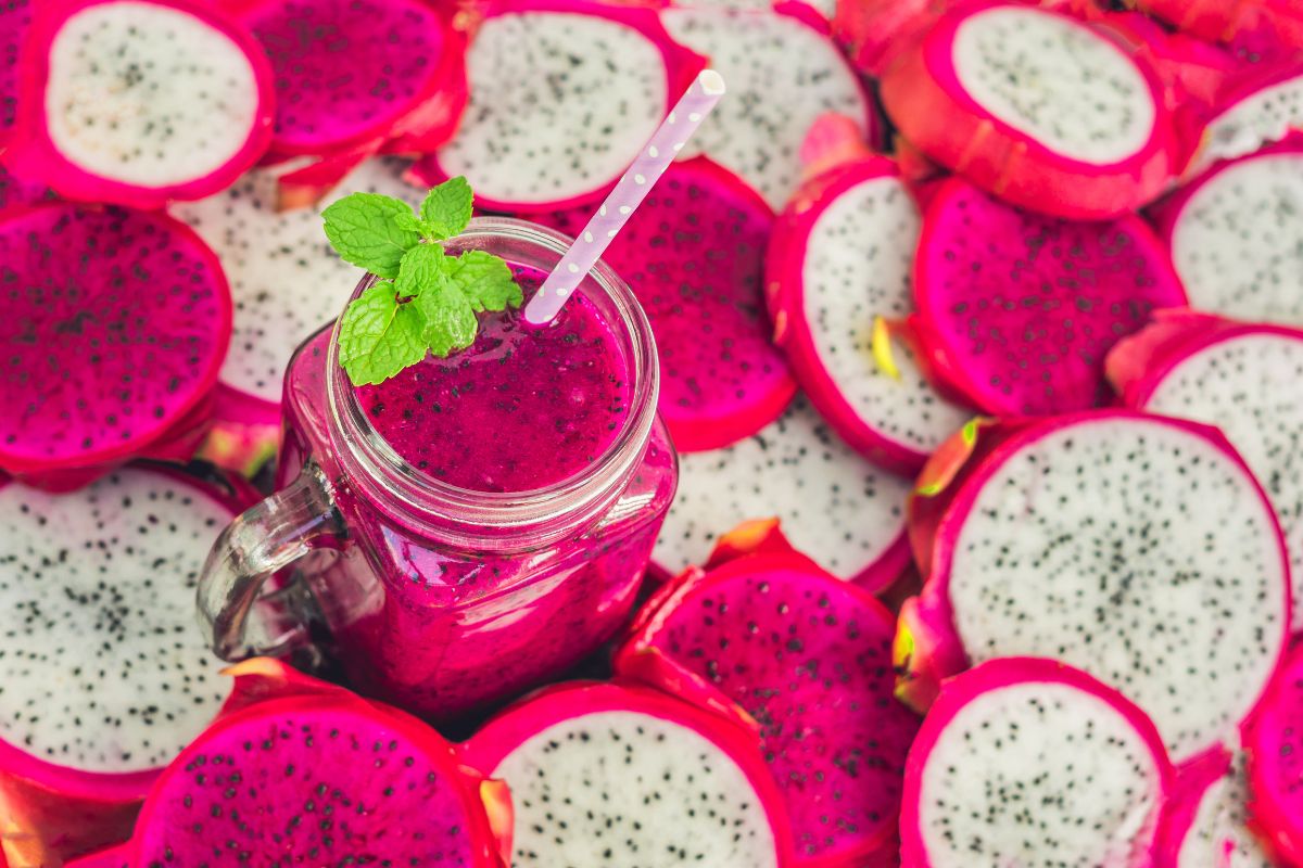 Dragon fruit smoothie with many dragon fruit in the background. 
