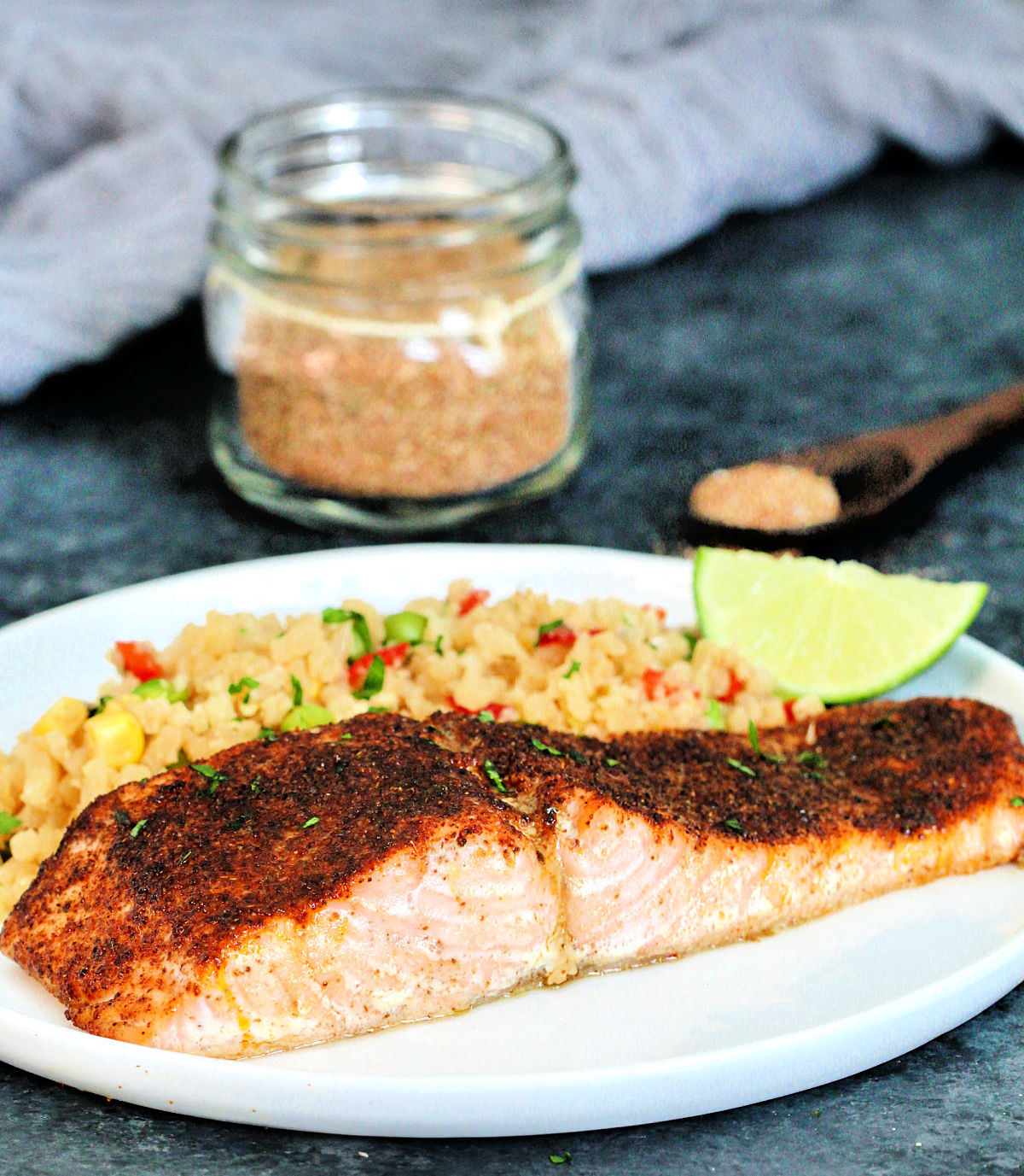 A plate of salmon prepared with the Best Ever Salmon Dry Rub with a jar of the rub in the background.