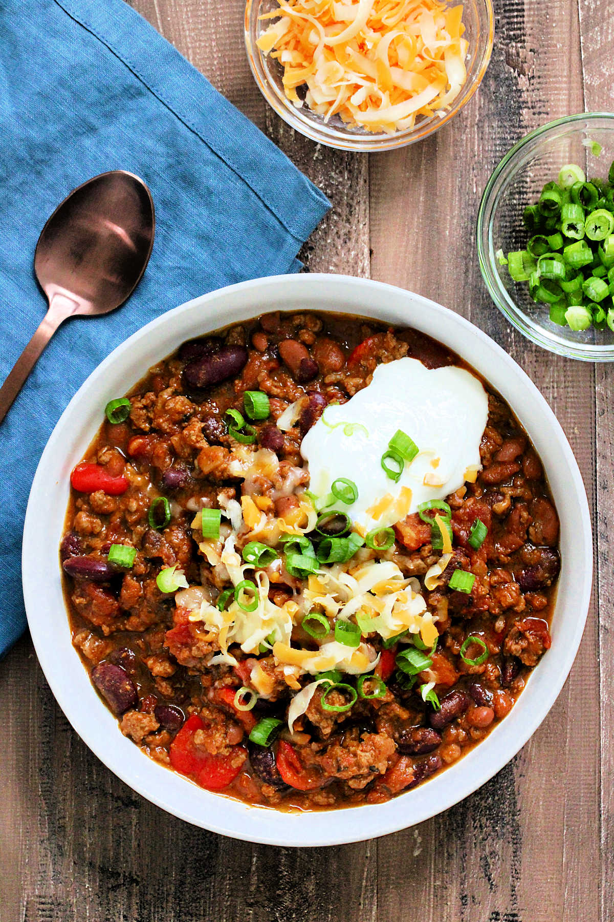 Bowl of hearty pumpkin chili topped with cheese, sour cream and scallions