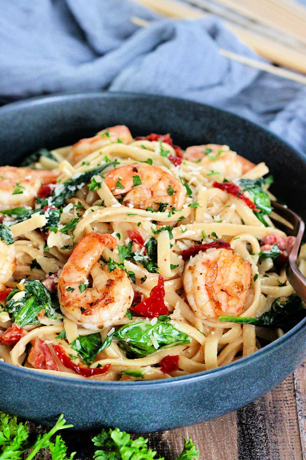 Shrimp & Spinach Pasta in a gray bowl on wooden board